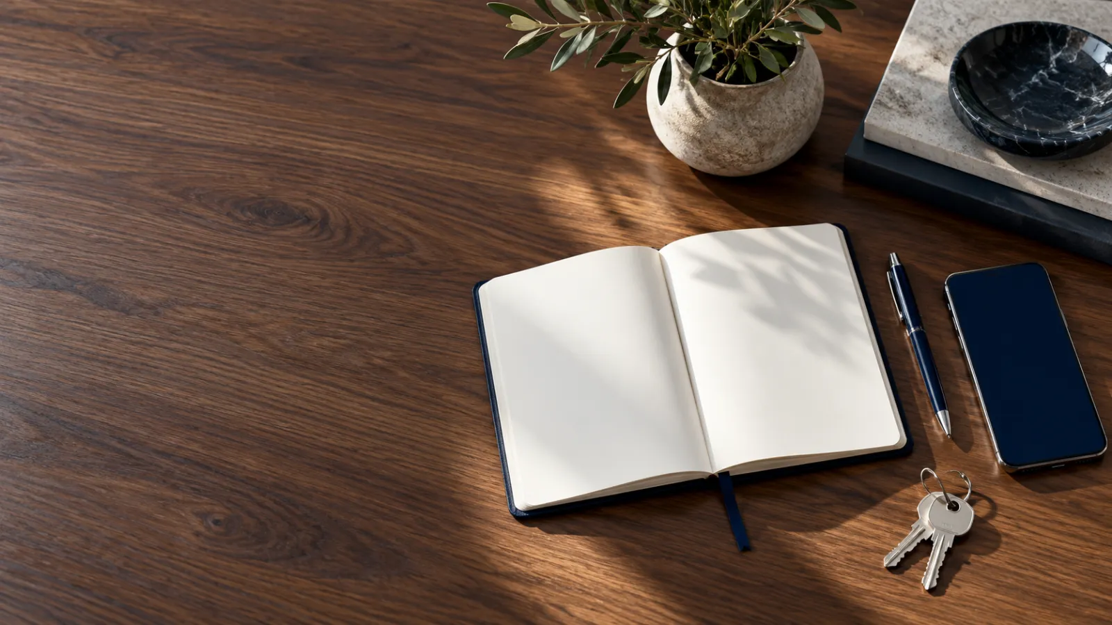 Un cuaderno abierto, un bolígrafo y unas llaves sobre una mesa